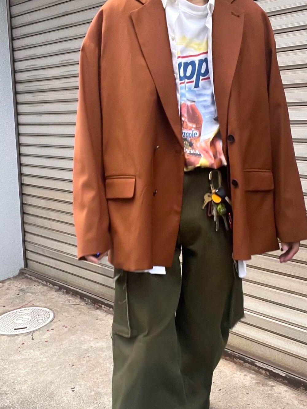 グリーン系のカーゴパンツ、シルバー系のスニーカー、オレンジ系のテーラードジャケットを着用したメンズの秋コーディネートの2枚目の写真