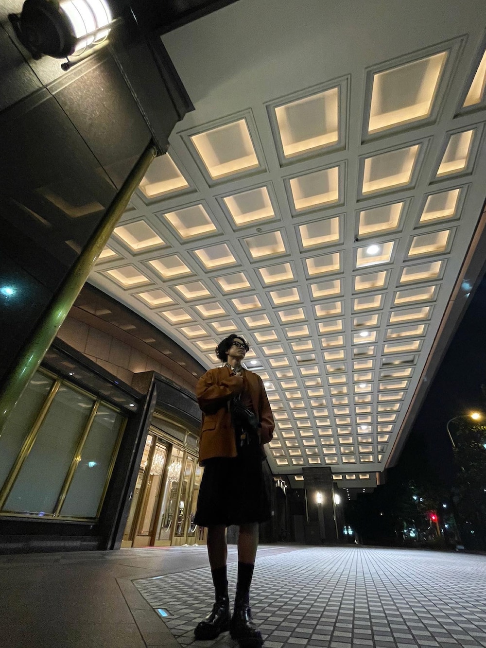 オレンジ系のテーラードジャケット、オレンジ系のポロシャツ、ブラック系のショルダーバッグを着用したメンズの秋コーディネートの2枚目の写真