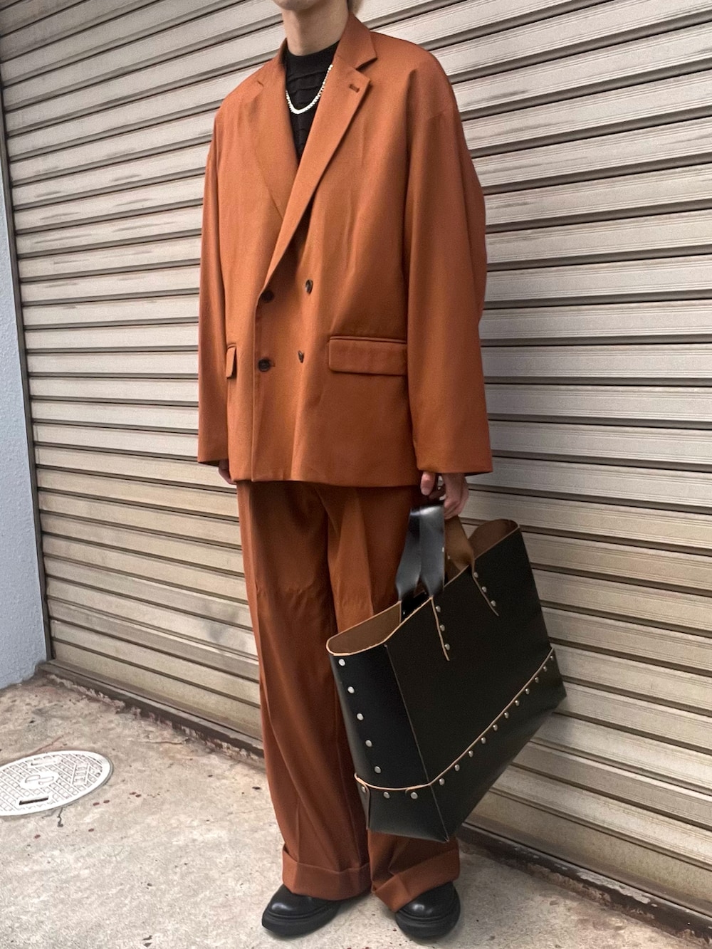 ブラック系のブーツ、オレンジ系のスラックス、オレンジ系のテーラードジャケットを着用したメンズの秋コーディネートの2枚目の写真