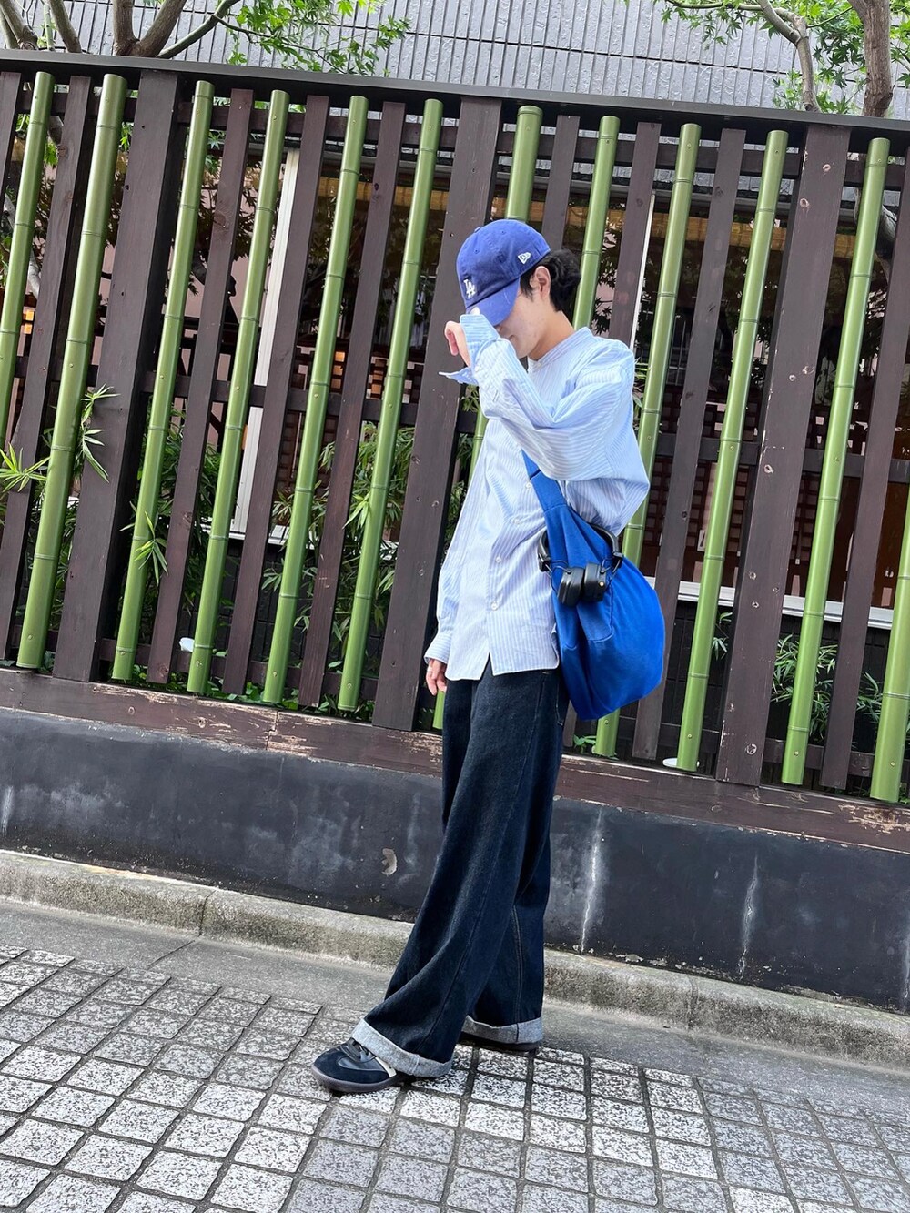 ブラック系のスニーカー、ブルー系のデニムパンツ、ブルー系のキャップを着用したメンズの秋コーディネートの2枚目の写真