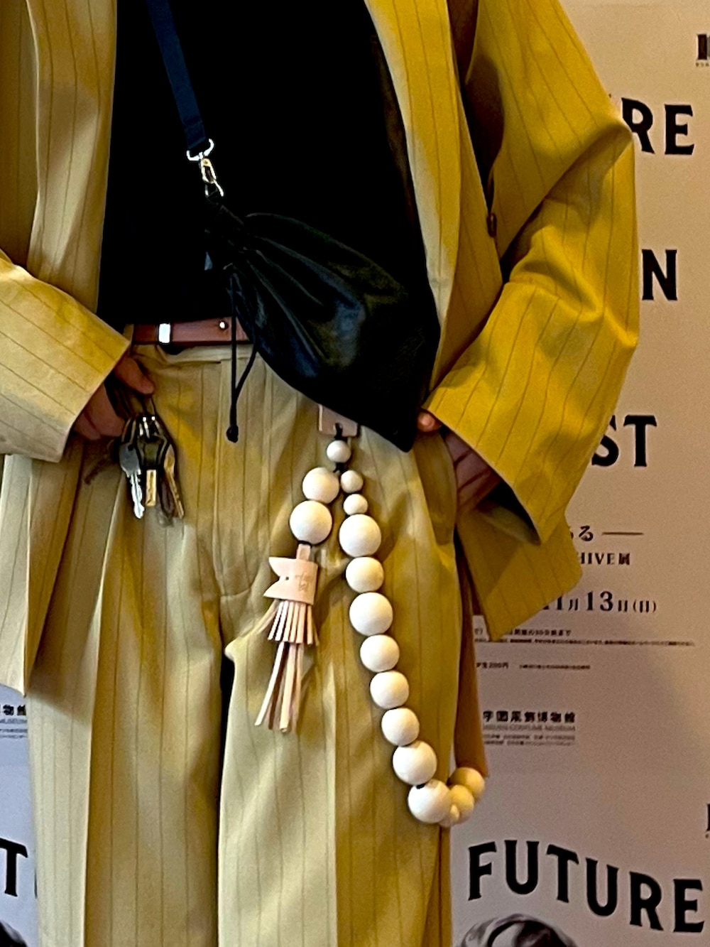 ブラック系のブーツ、イエロー系のスラックス、ブラック系のショルダーバッグを着用したメンズの秋コーディネートの2枚目の写真