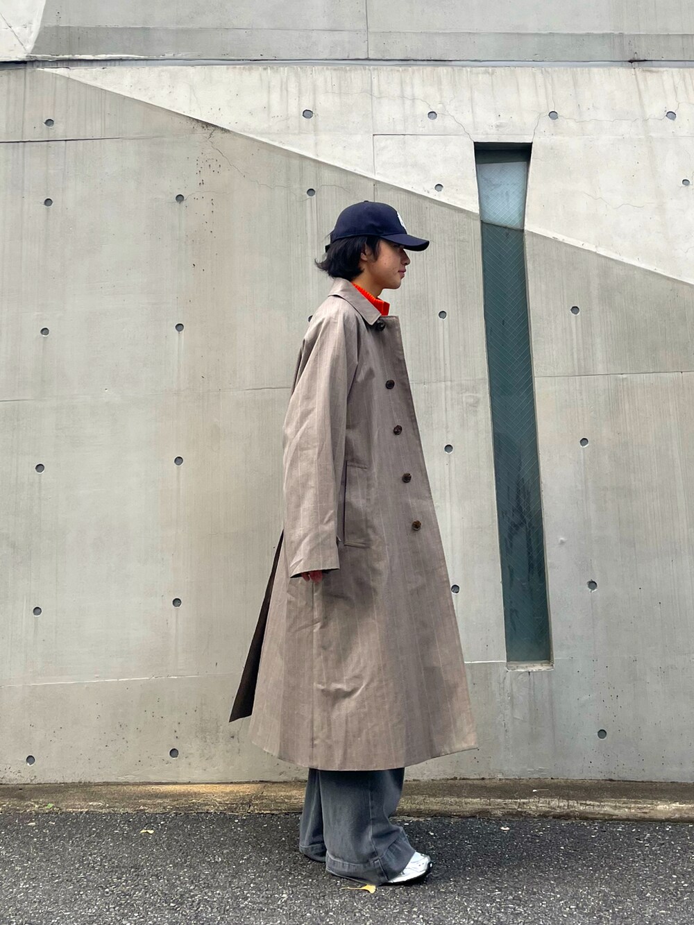 グレー系のデニムパンツ、シルバー系のスニーカー、オレンジ系のトップスを着用したメンズの秋コーディネートの2枚目の写真
