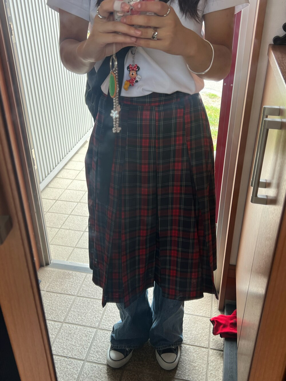 ホワイト系のTシャツ/カットソー、レッド系のスカート、ブルー系のデニムパンツを着用したレディースの秋コーディネートの2枚目の写真