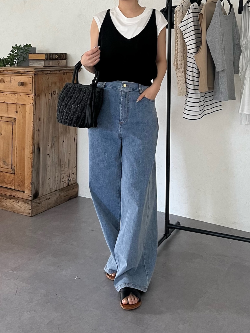 ブラック系のサンダル、ブルー系のデニムパンツ、ブラック系のバッグを着用したレディースの夏コーディネートの2枚目の写真