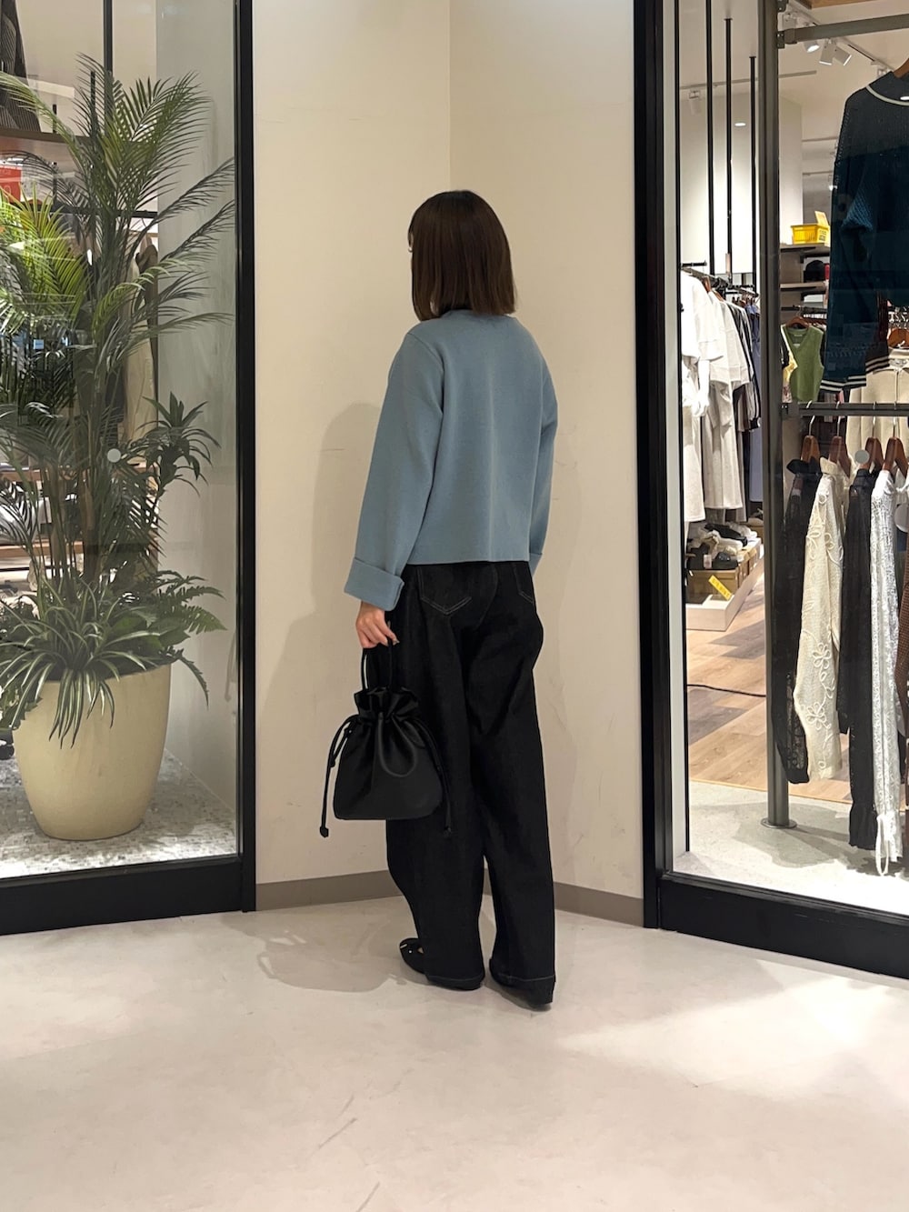 ブラック系のショルダーバッグ、ブラック系のデニムパンツ、ブラック系のブーツを着用したレディースの秋コーディネートの2枚目の写真