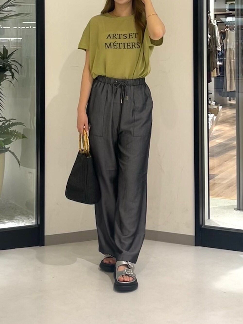 シルバー系のシューズ、ブラック系のパンツ、ブラック系のバッグを着用したレディースの夏コーディネートの3枚目の写真