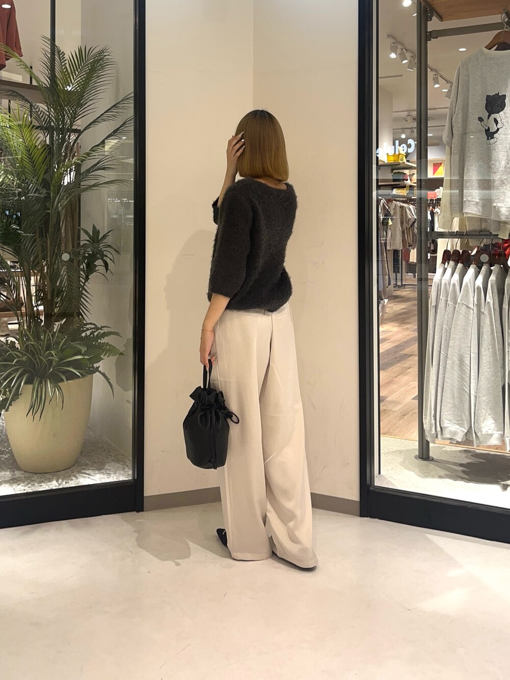 ブラック系のショルダーバッグ、ホワイト系のパンツ、グレー系のニット/セーターを着用したレディースの夏コーディネートの2枚目の写真