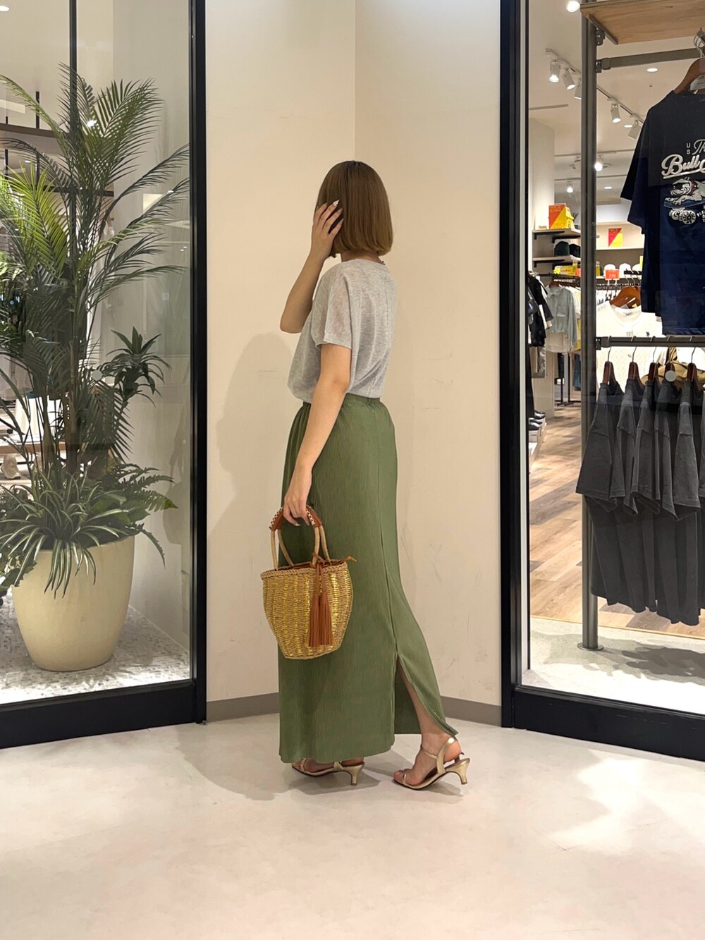 グレー系のニット/セーター、ベージュ系のバッグ、グリーン系のスカートを着用したレディースの夏コーディネートの3枚目の写真