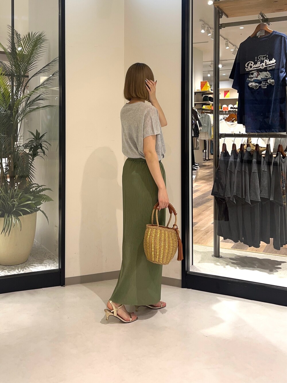 グレー系のニット/セーター、ベージュ系のバッグ、グリーン系のスカートを着用したレディースの夏コーディネートの2枚目の写真