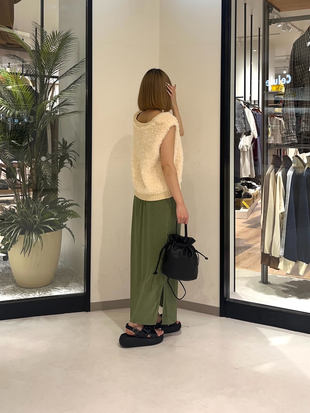 グリーン系のスカート、ホワイト系のカーディガン/ボレロ、ブラック系のショルダーバッグを着用したレディースの夏コーディネートの2枚目の写真