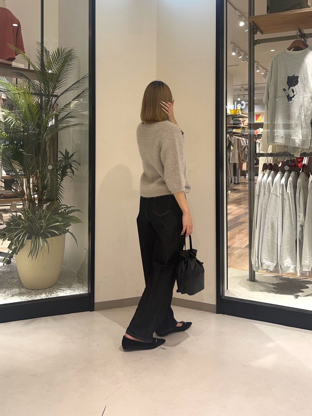 ベージュ系のニット/セーター、ブラック系のデニムパンツ、ブラック系のショルダーバッグを着用したレディースの夏コーディネートの3枚目の写真