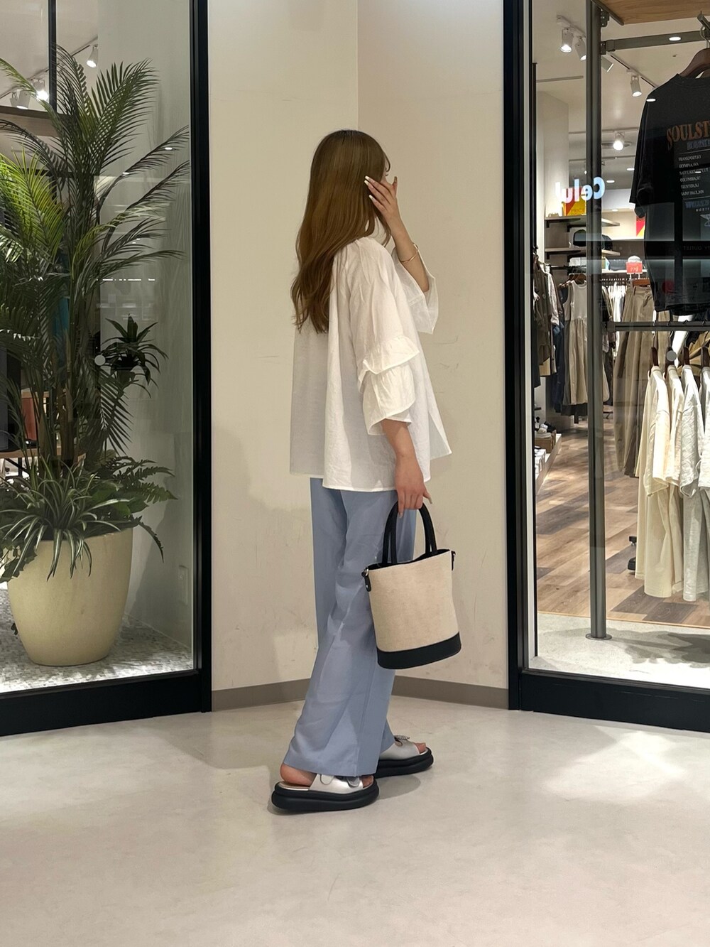 ホワイト系のトップス、ブラック系のバッグ、ブルー系のパンツを着用したレディースの夏コーディネートの2枚目の写真