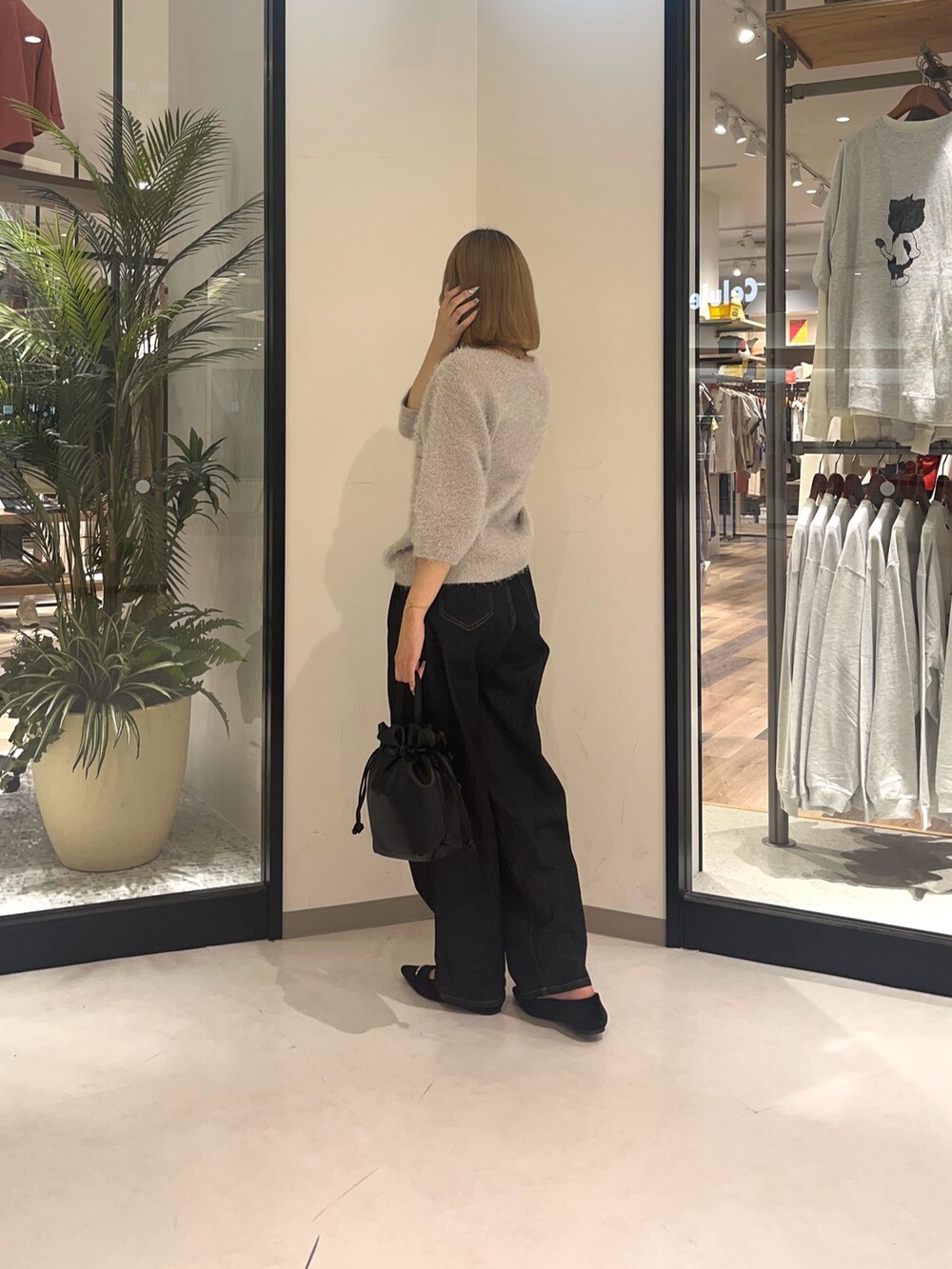 ベージュ系のニット/セーター、ブラック系のデニムパンツ、ブラック系のショルダーバッグを着用したレディースの夏コーディネートの2枚目の写真