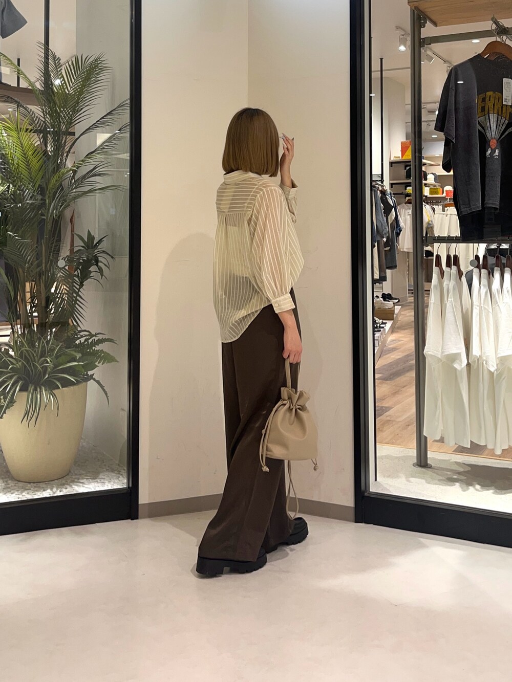 ホワイト系のシャツ/ブラウス、ブラウン系のパンツ、ブラウン系のショルダーバッグを着用したレディースの夏コーディネートの2枚目の写真