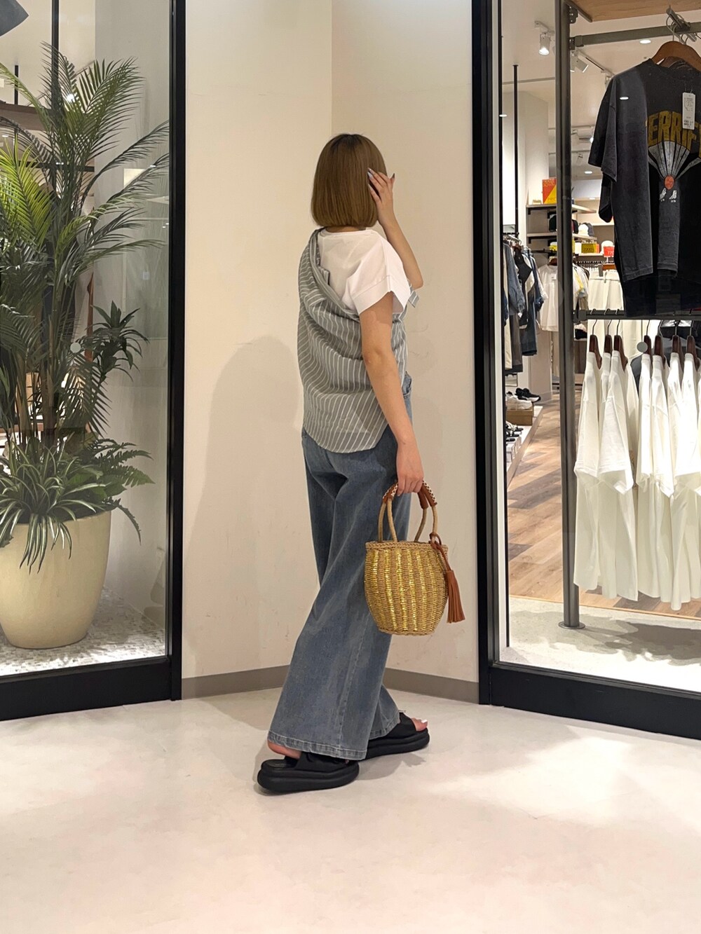 ベージュ系のバッグ、ブルー系のデニムパンツ、ブラック系のシューズを着用したレディースの夏コーディネートの3枚目の写真