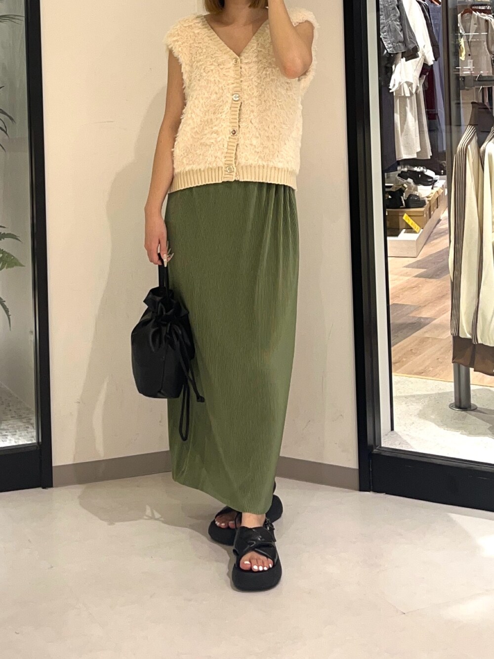 グリーン系のスカート、ホワイト系のカーディガン/ボレロ、ブラック系のショルダーバッグを着用したレディースの夏コーディネートの3枚目の写真