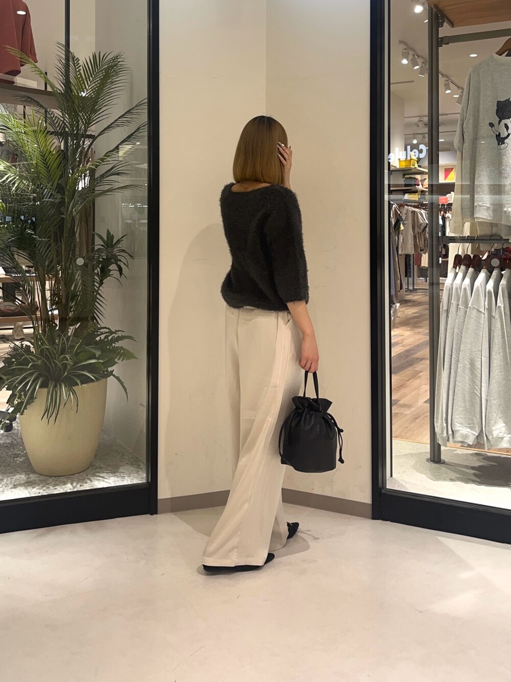 ブラック系のショルダーバッグ、ホワイト系のパンツ、グレー系のニット/セーターを着用したレディースの夏コーディネートの3枚目の写真