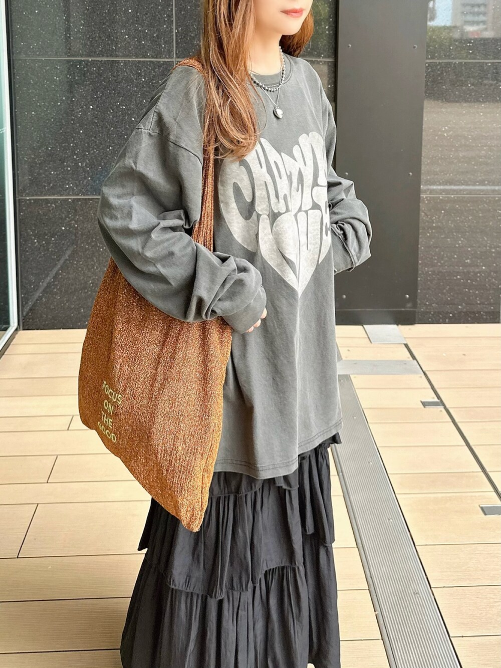 ブラック系のTシャツ/カットソー、ブラック系のスカート、オレンジ系のトートバッグを着用したレディースの秋コーディネートの2枚目の写真