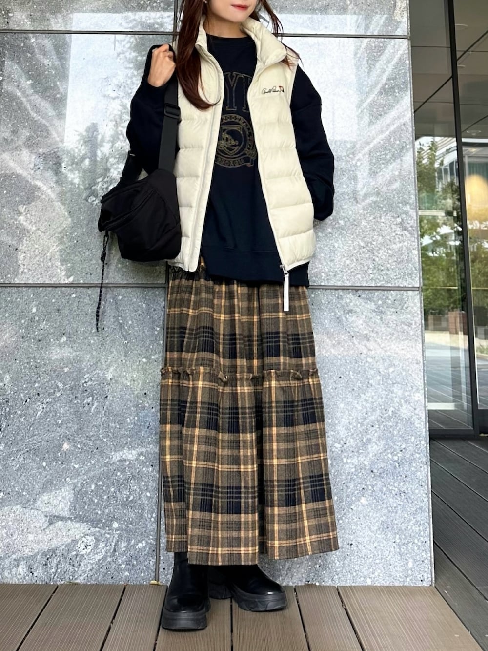 ブルー系のスウェット、ホワイト系のダウンベスト、イエロー系のスカートを着用したレディースの秋コーディネートの2枚目の写真