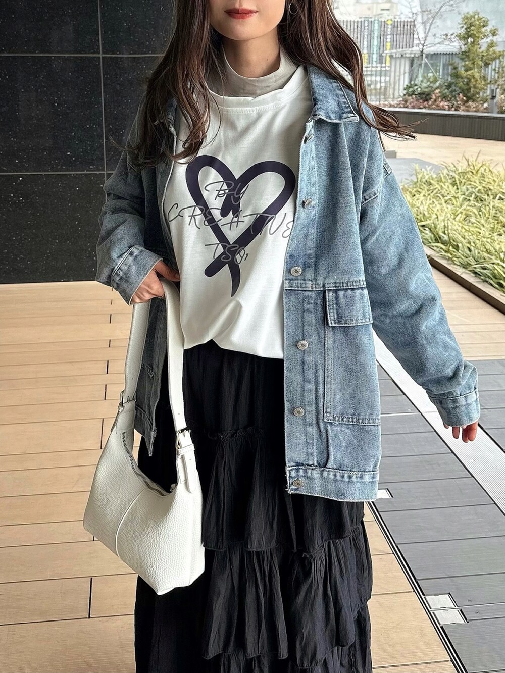 ブルー系のデニムジャケット、ホワイト系のTシャツ/カットソー、ブラック系のスカートを着用したレディースの冬コーディネートの3枚目の写真