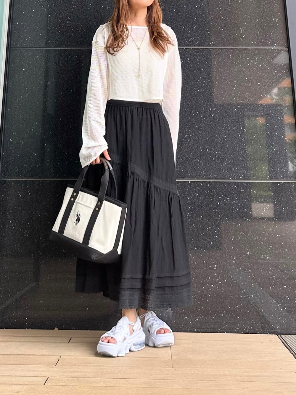 ホワイト系のトートバッグ、ベージュ系のワンピース、ブラック系のスカートを着用したレディースの夏コーディネートの2枚目の写真