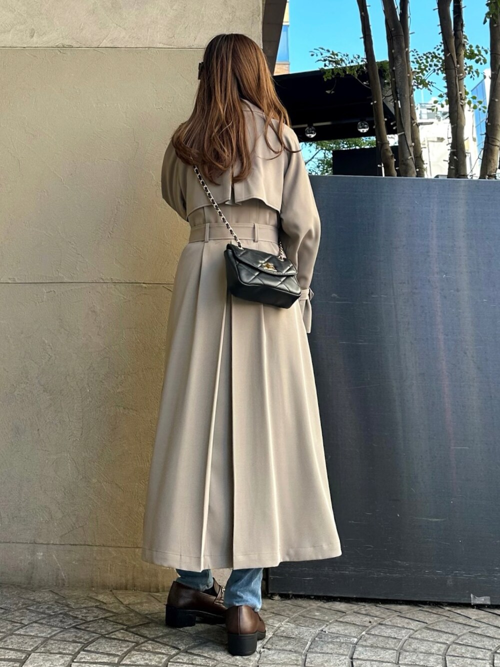 ベージュ系のトレンチコート、ブラック系のTシャツ/カットソー、ブラック系のワンピース/ドレスを着用したレディースの冬コーディネートの2枚目の写真