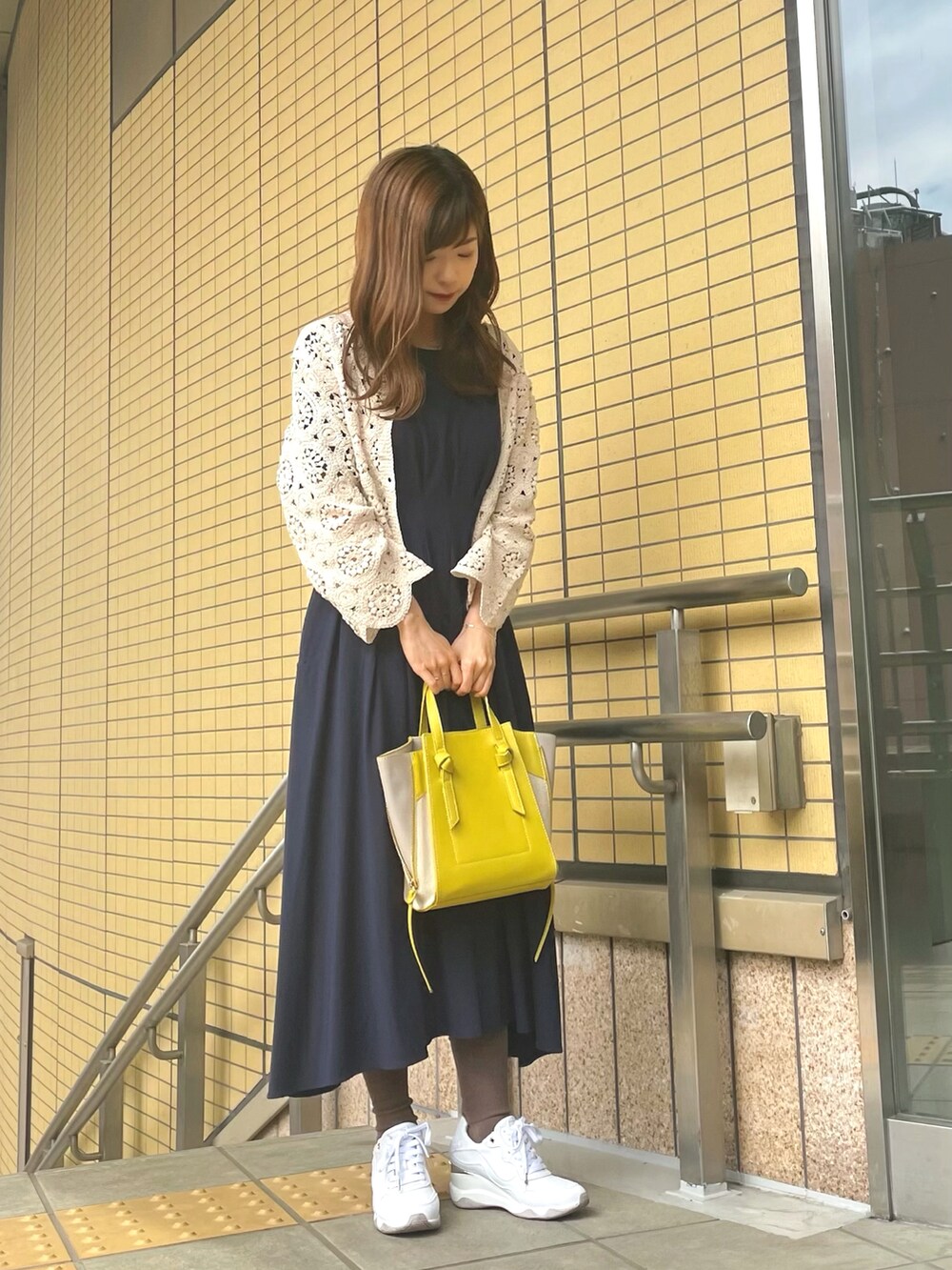 イエロー系のショルダーバッグ、ホワイト系のカーディガン/ボレロ、ブルー系のワンピースを着用したレディースの春コーディネートの2枚目の写真
