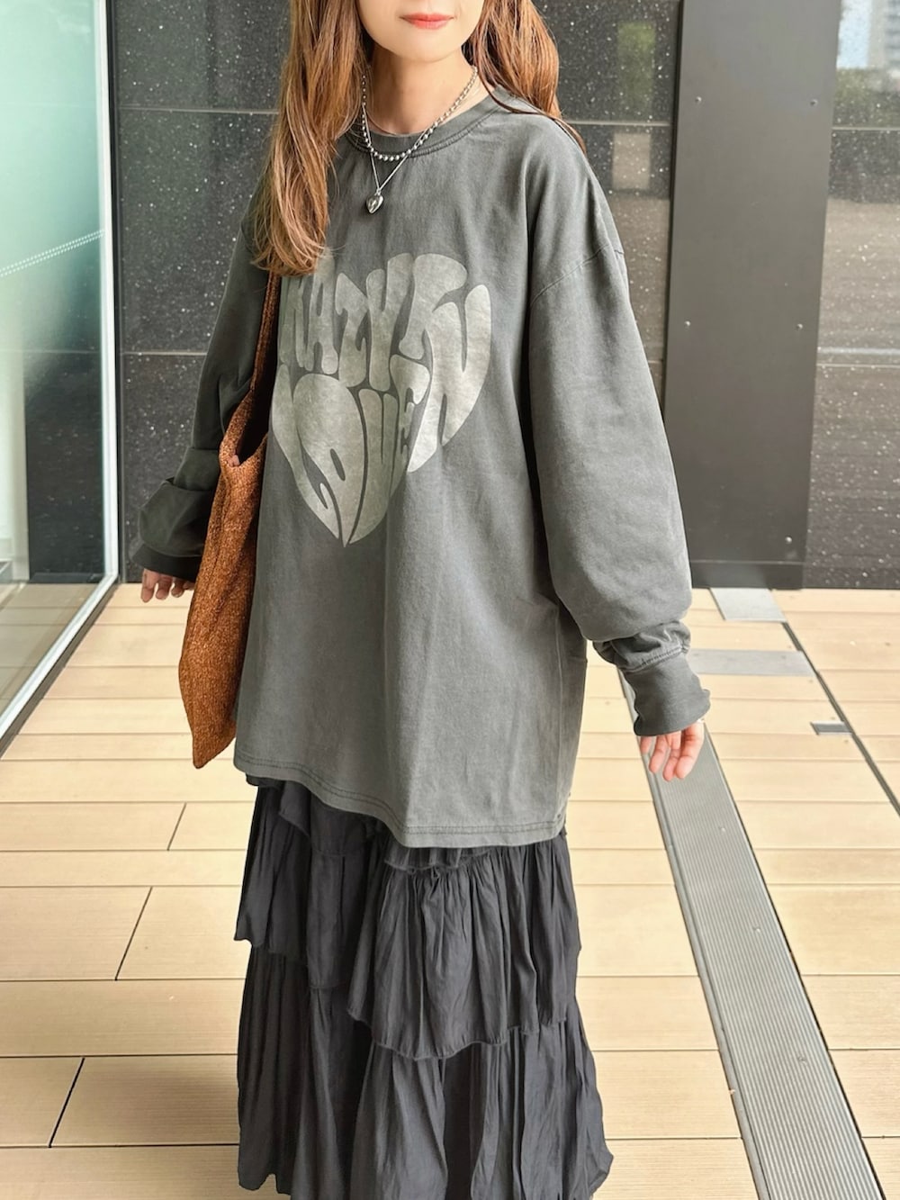 ブラック系のTシャツ/カットソー、ブラック系のスカート、オレンジ系のトートバッグを着用したレディースの秋コーディネートの3枚目の写真