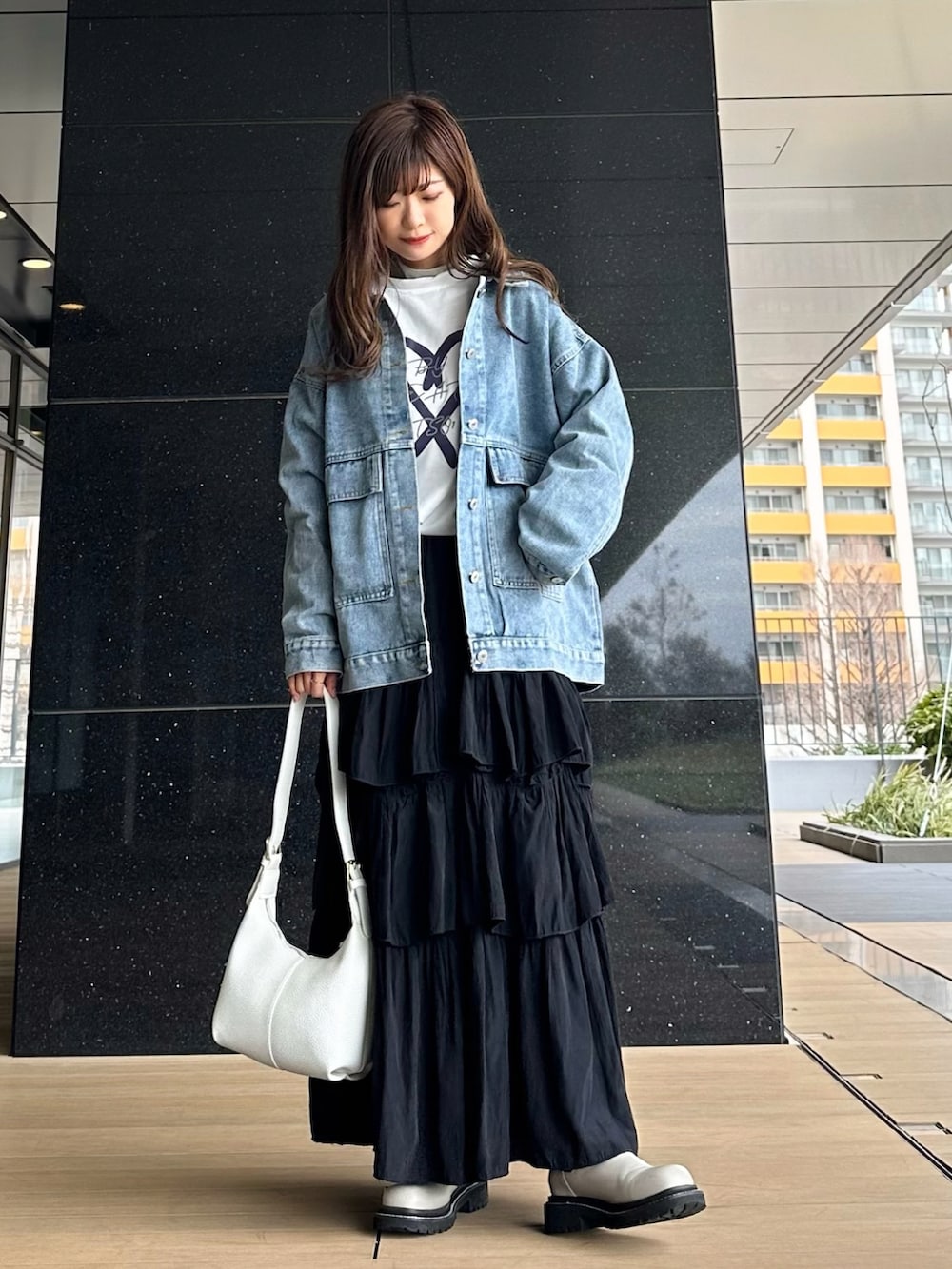 ブルー系のデニムジャケット、ホワイト系のTシャツ/カットソー、ブラック系のスカートを着用したレディースの冬コーディネートの2枚目の写真