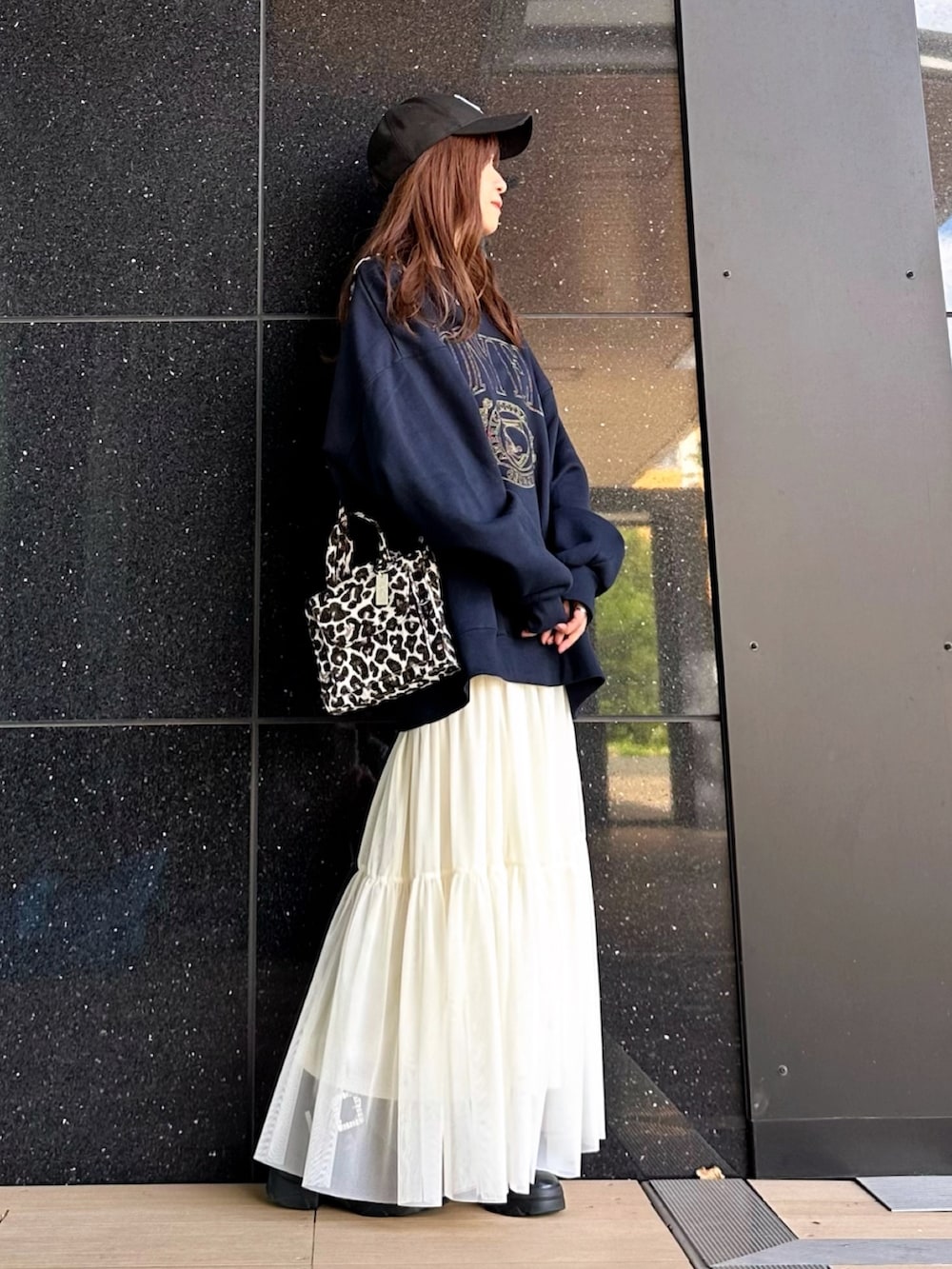 ブルー系のスウェット、ホワイト系のスカート、ブラック系のショルダーバッグを着用したレディースの秋コーディネートの2枚目の写真