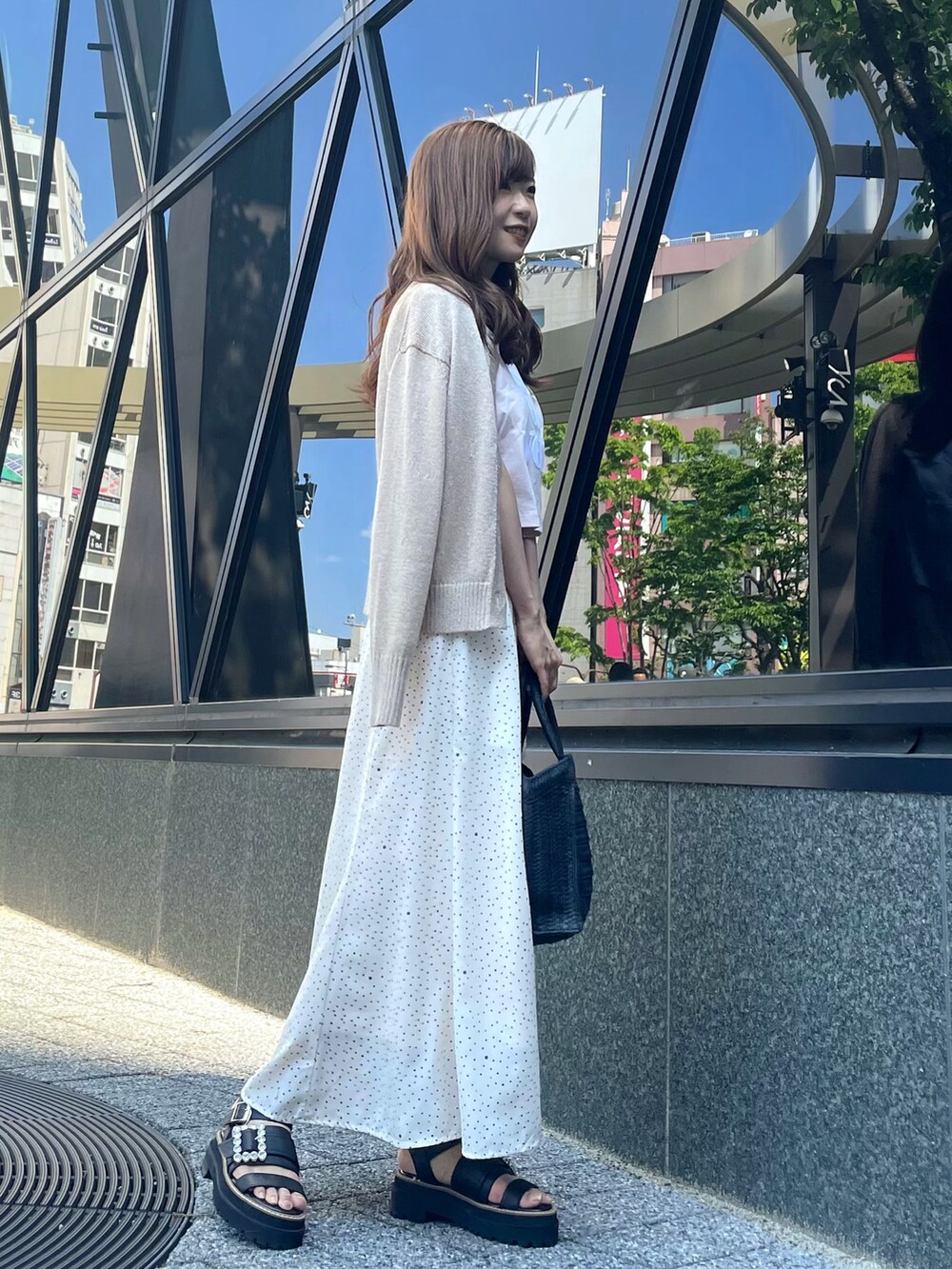 ピンク系のTシャツ/カットソー、ホワイト系のスカート、ブラック系のかごバッグを着用したレディースの春コーディネートの2枚目の写真