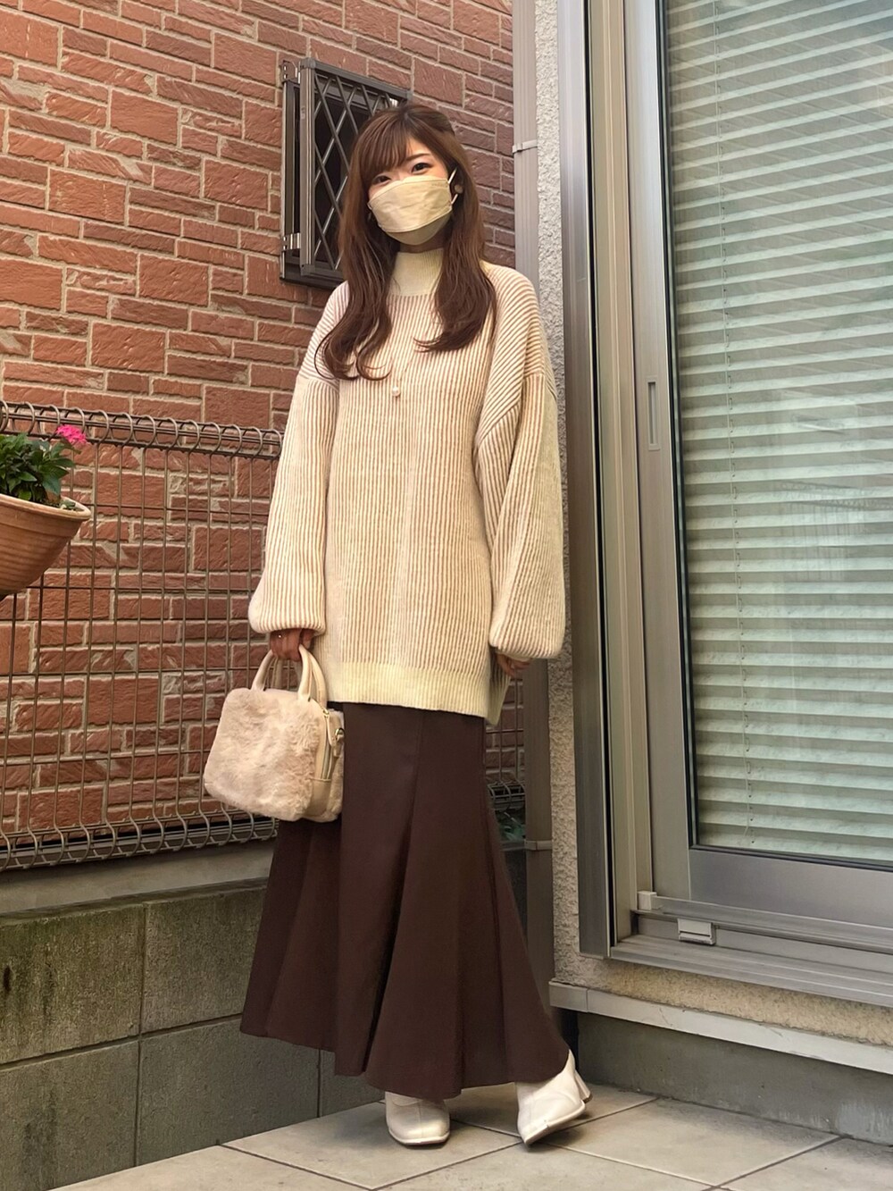 ホワイト系のショルダーバッグ、ピンク系のニット/セーター、ブラウン系のスカートを着用したレディースの秋コーディネートの2枚目の写真