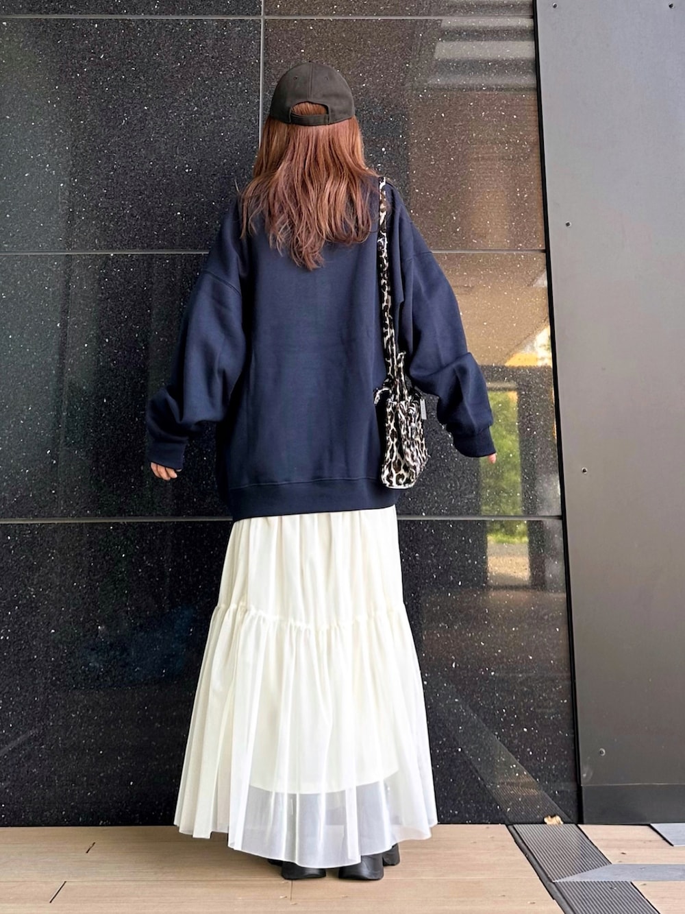 ブルー系のスウェット、ホワイト系のスカート、ブラック系のショルダーバッグを着用したレディースの秋コーディネートの4枚目の写真