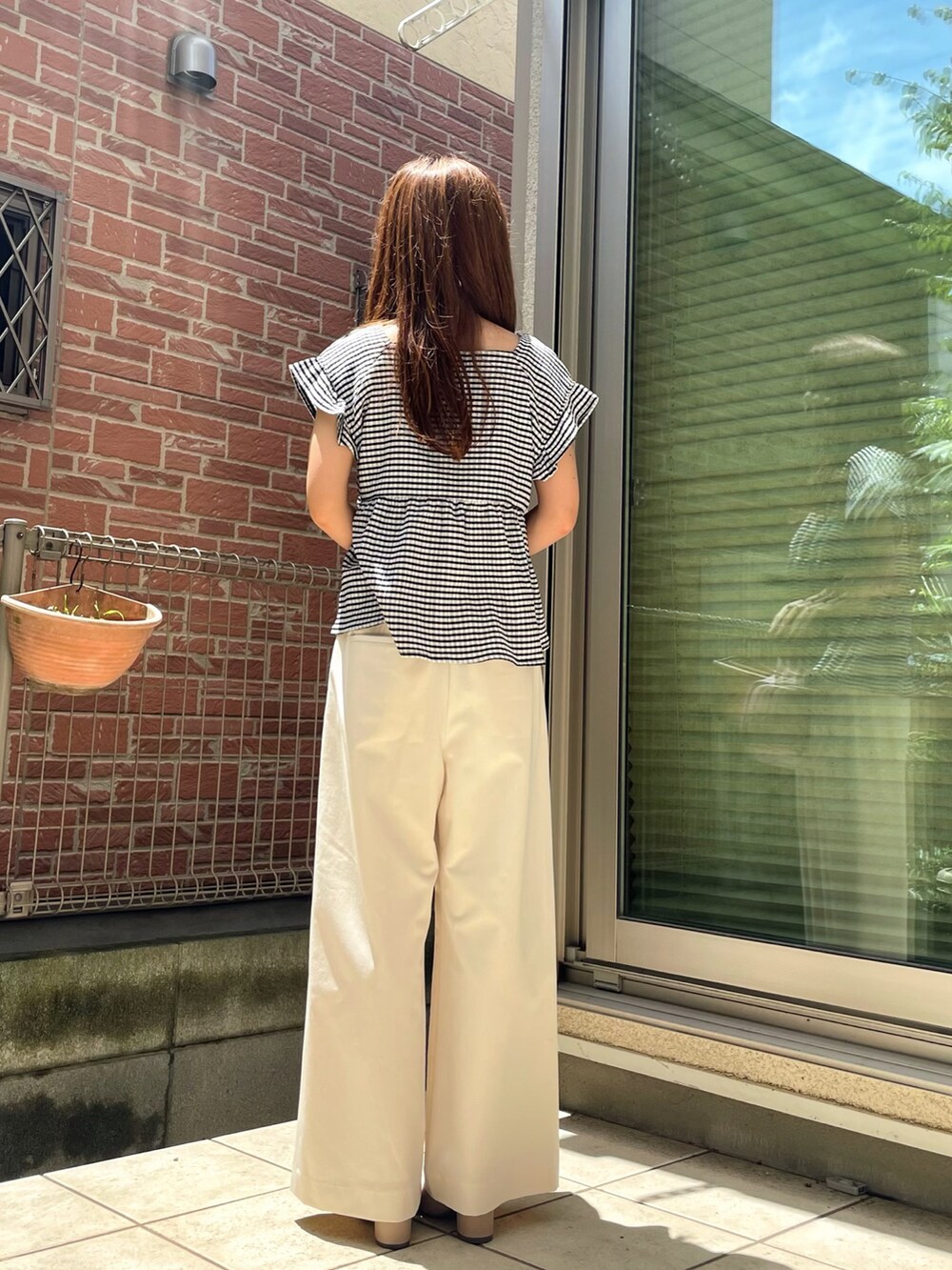 ホワイト系のパンツ、ブラック系のTシャツ/カットソー、ピンク系のショルダーバッグを着用したレディースの夏コーディネートの2枚目の写真