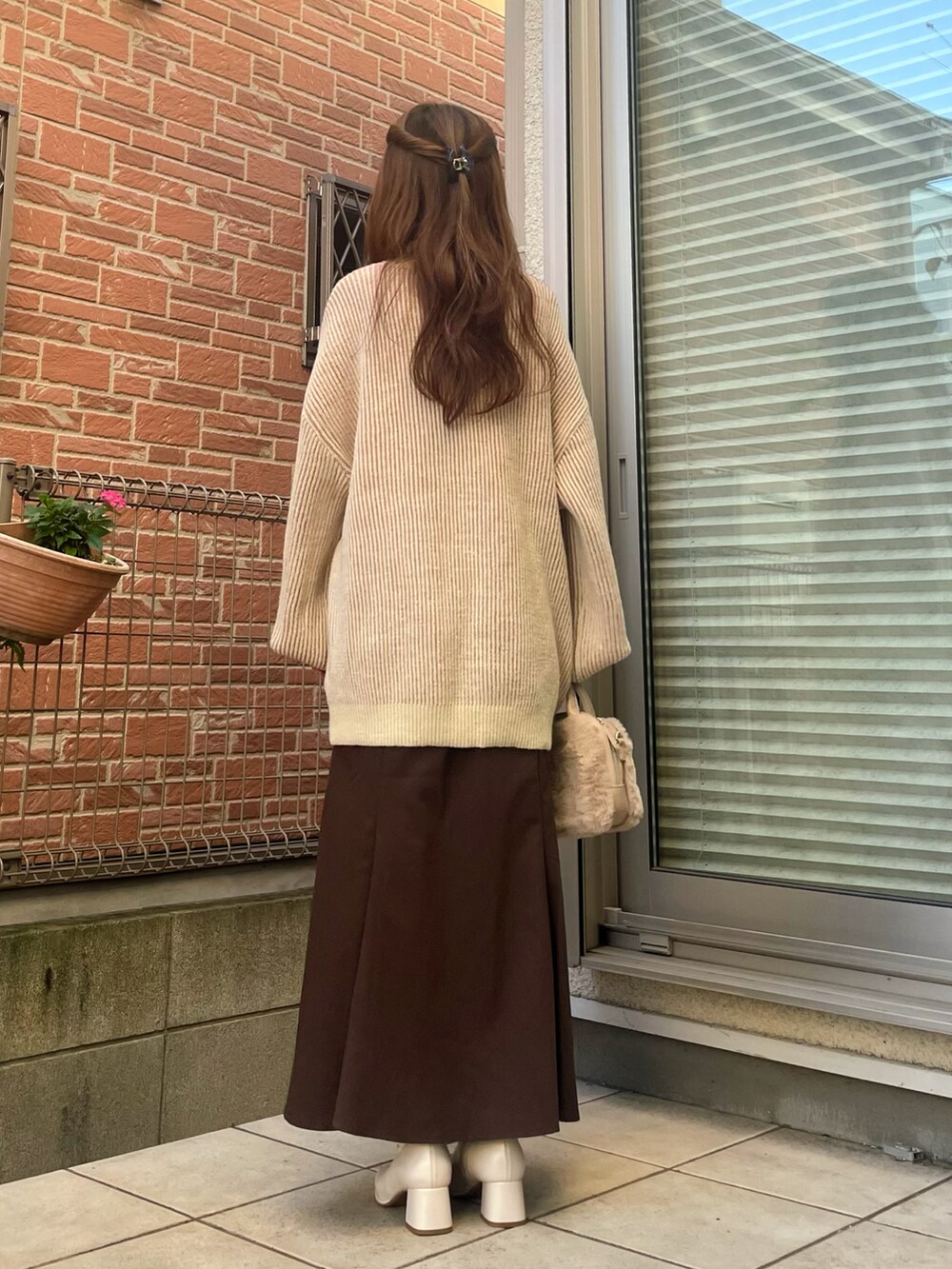 ホワイト系のショルダーバッグ、ピンク系のニット/セーター、ブラウン系のスカートを着用したレディースの秋コーディネートの3枚目の写真