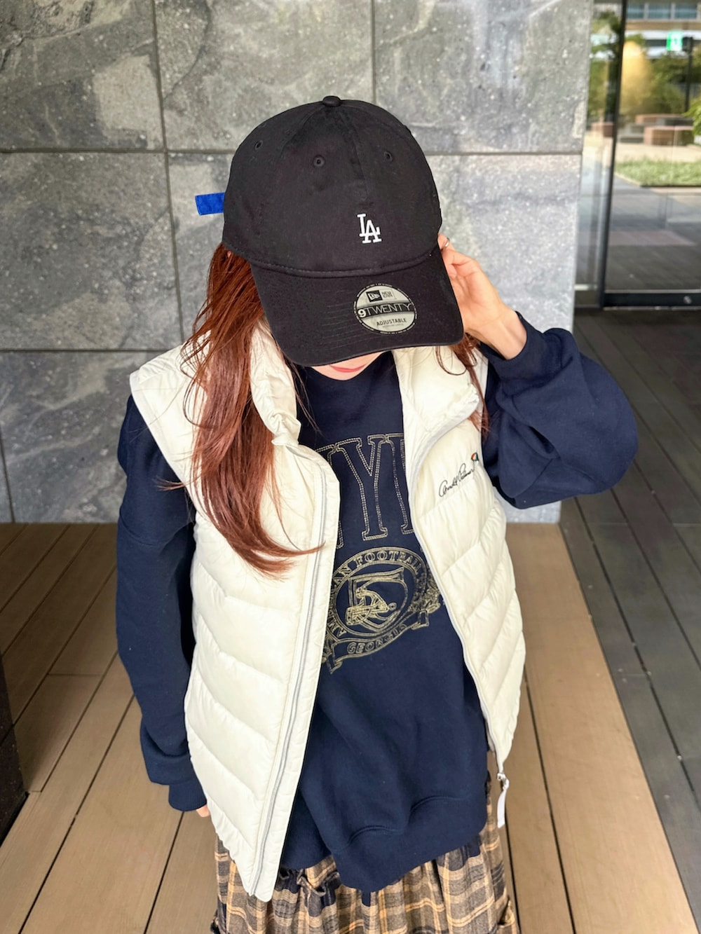 ブルー系のスウェット、ホワイト系のダウンベスト、イエロー系のスカートを着用したレディースの秋コーディネートの4枚目の写真