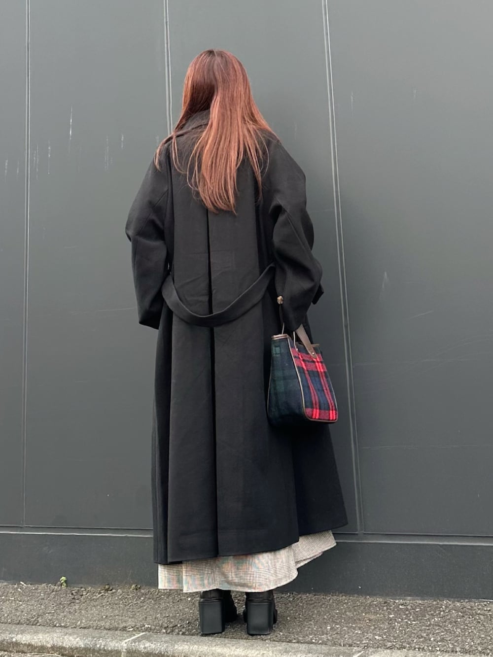 ブラック系のステンカラーコート、レッド系のトートバッグ、ブラウン系のブーツを着用したレディースの秋コーディネートの4枚目の写真