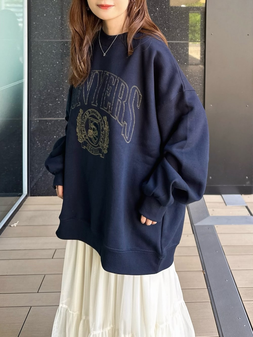 ブルー系のスウェット、ホワイト系のスカート、ブラック系のショルダーバッグを着用したレディースの秋コーディネートの3枚目の写真