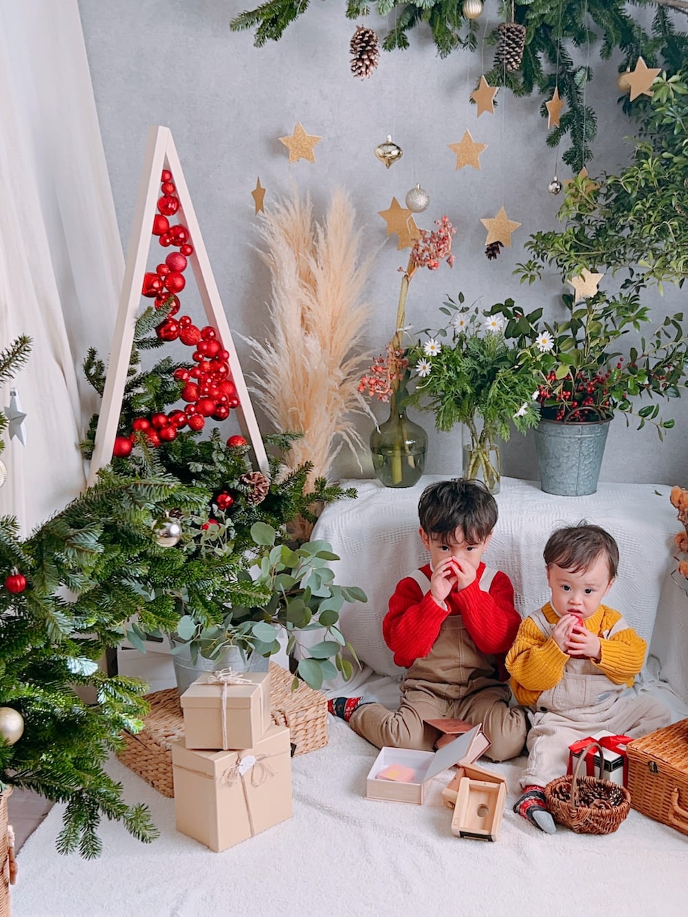 レッド系のニット/セーター、イエロー系のニット/セーター、ベージュ系のサロペット/オーバーオールを着用したキッズの冬コーディネートの3枚目の写真