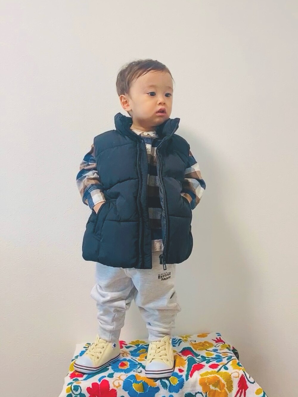 ブラック系のダウンベスト、グレー系のスウェットパンツ、ホワイト系のスニーカーを着用したキッズの冬コーディネートの2枚目の写真