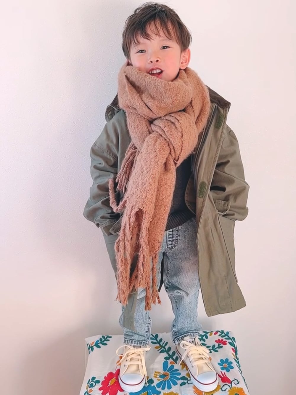 グリーン系のモッズコート、ブルー系のデニムパンツ、ホワイト系のスニーカーを着用したキッズの秋コーディネートの3枚目の写真