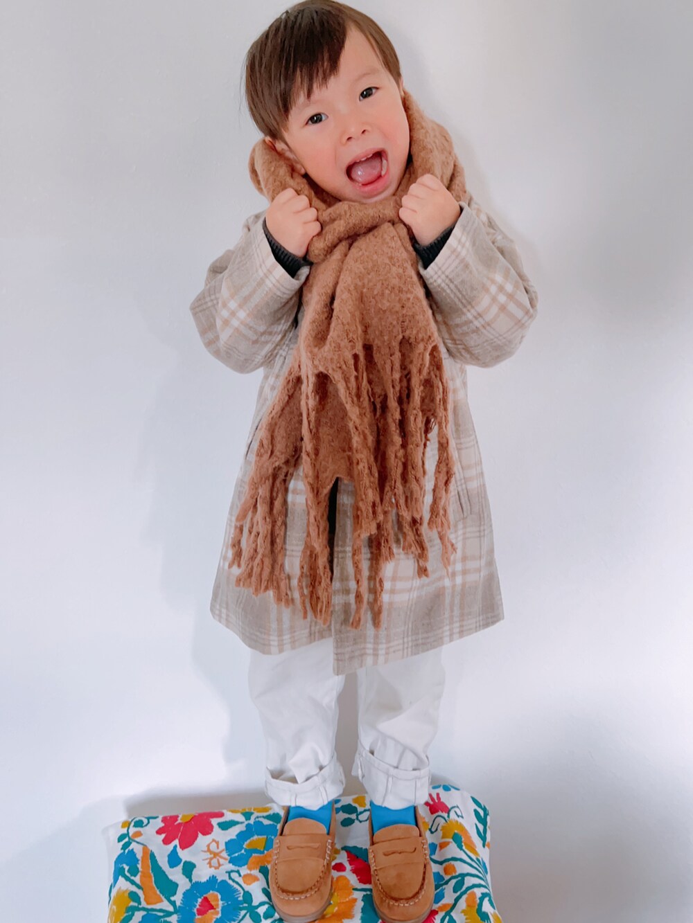 ベージュ系のチェスターコート、グレー系のニット/セーター、ホワイト系のパンツを着用したキッズの秋コーディネートの4枚目の写真