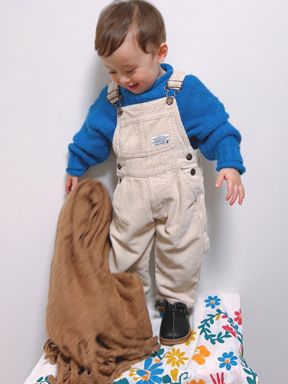 ベージュ系のサロペット/オーバーオール、ブルー系のニット/セーター、ブラック系のシューズを着用したキッズの冬コーディネートの2枚目の写真