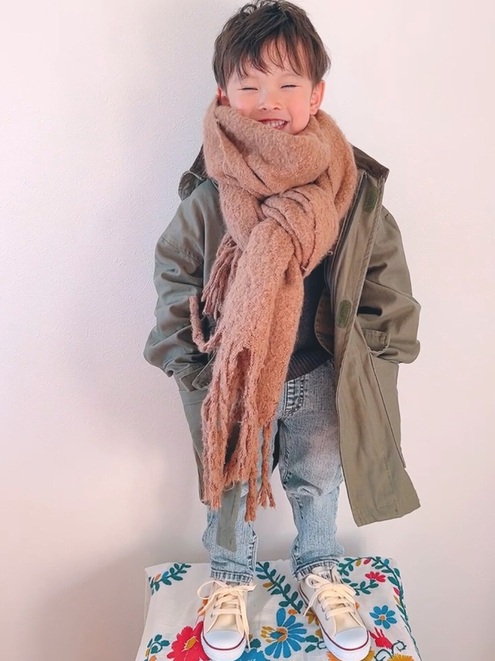 グリーン系のモッズコート、ブルー系のデニムパンツ、ホワイト系のスニーカーを着用したキッズの秋コーディネートの2枚目の写真