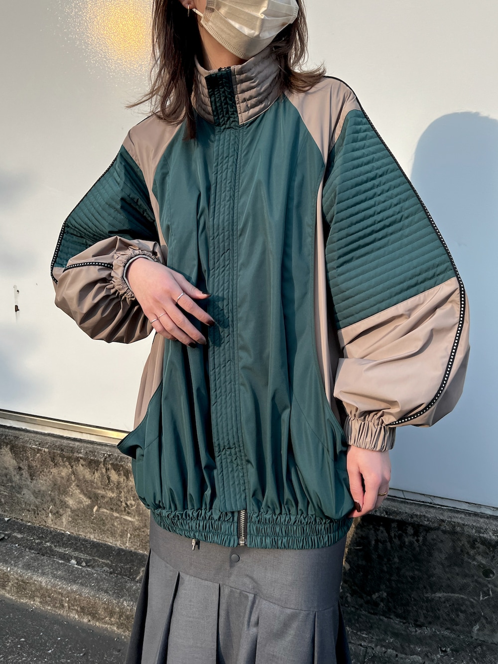 ベージュ系のブルゾン、グレー系のスカートを着用したレディースの春コーディネートの3枚目の写真