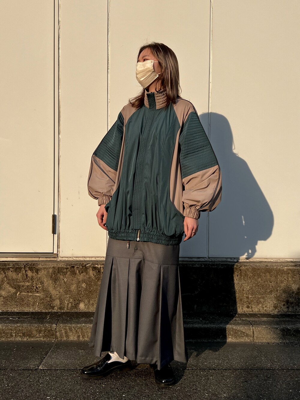 ベージュ系のブルゾン、グレー系のスカートを着用したレディースの春コーディネートの2枚目の写真