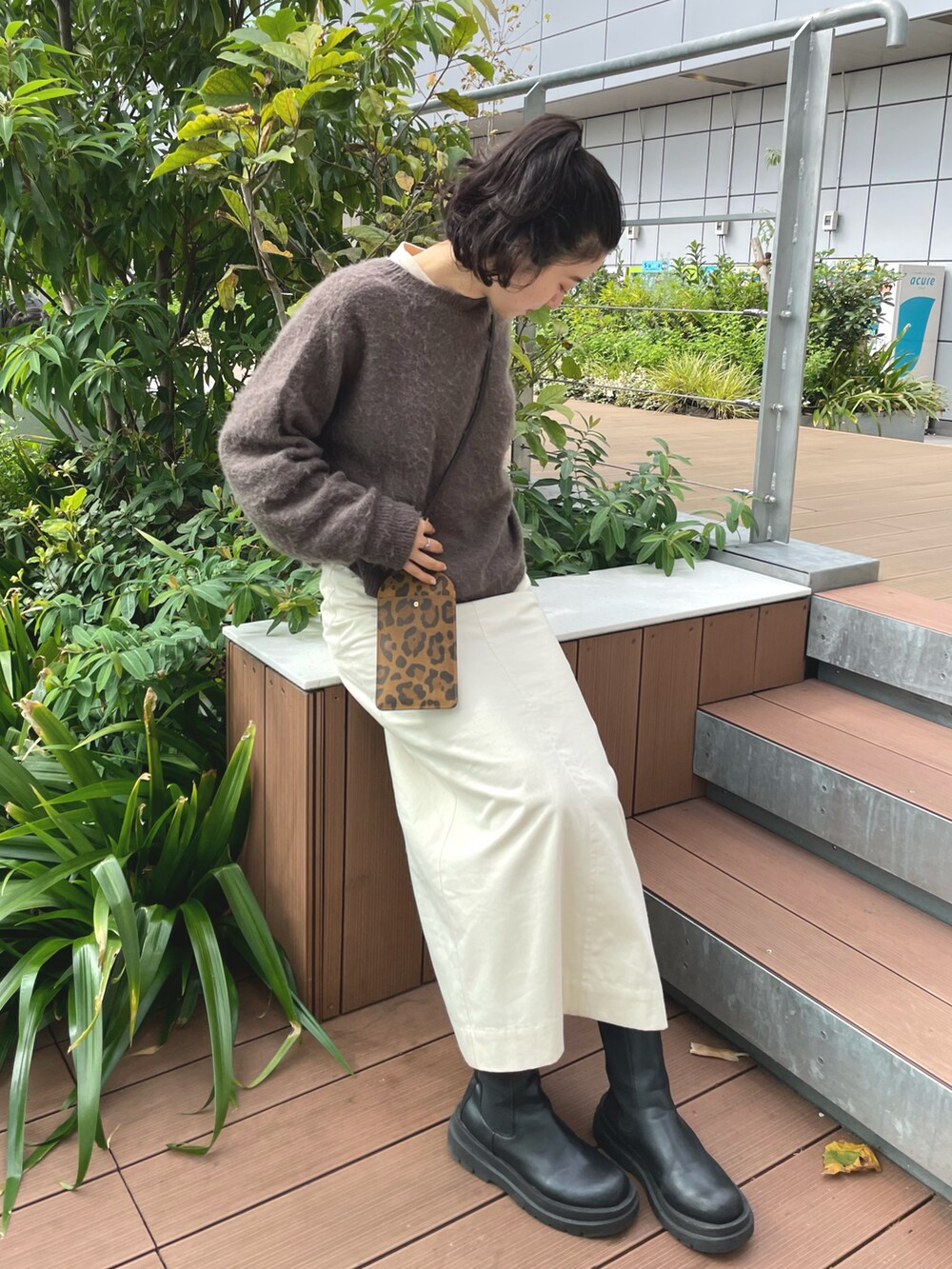 ベージュ系のスカート、ブラウン系のニット/セーターを着用したレディースの春コーディネートの2枚目の写真