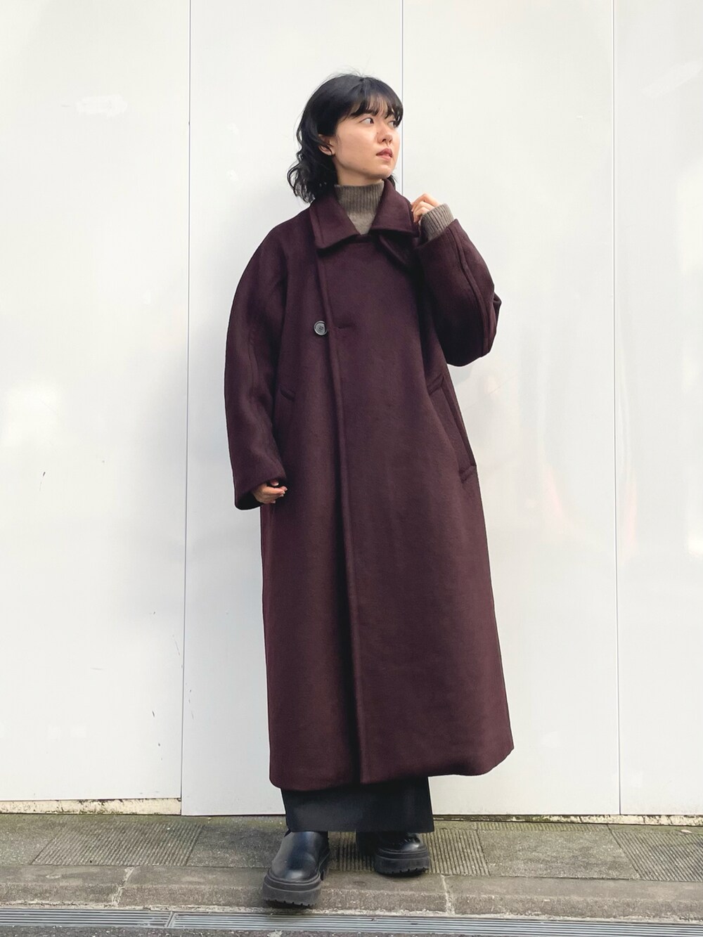 ブラック系のワンピース、レッド系のステンカラーコート、ブラウン系のニット/セーターを着用したレディースの冬コーディネートの2枚目の写真