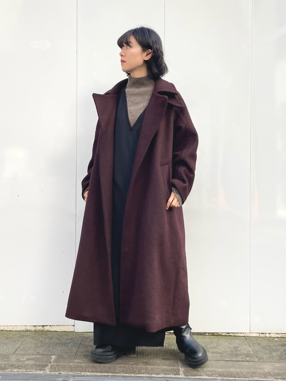 ブラック系のワンピース、レッド系のステンカラーコート、ブラウン系のニット/セーターを着用したレディースの冬コーディネートの3枚目の写真