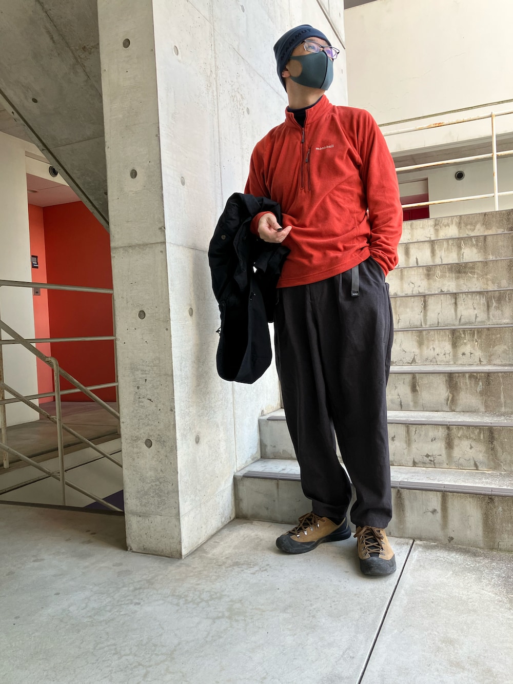 ブラック系のマウンテンパーカー、オレンジ系のシャツ/ブラウス、グレー系のその他パンツを着用したメンズの冬コーディネートの2枚目の写真